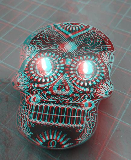 A circuit board in the style of a Day of the Dead skull, with glowing blue LEDs as eyes. Black and white anaglyph