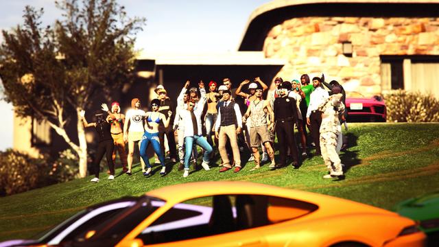 A screenshot I took in the video game GTA Online using the Rockstar Editor. It shows a group of online characters in front of a villa with two sports cars parked in the front.