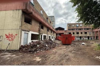 Derelict blocks of flats with large red skips in front of them