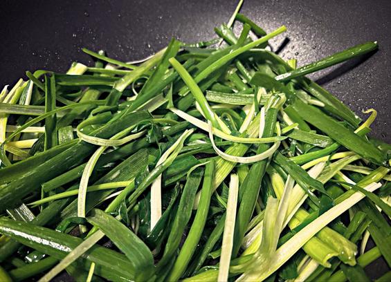 Chopped spring onions in a black wok
