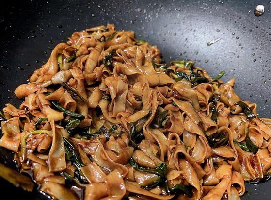A black wok with stir-fried noodles and vegetables.