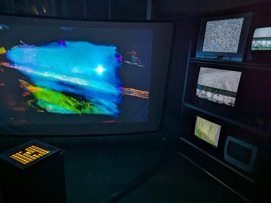 Array of five working screens and the one dead TV with a midi controller for changing the videos being shown