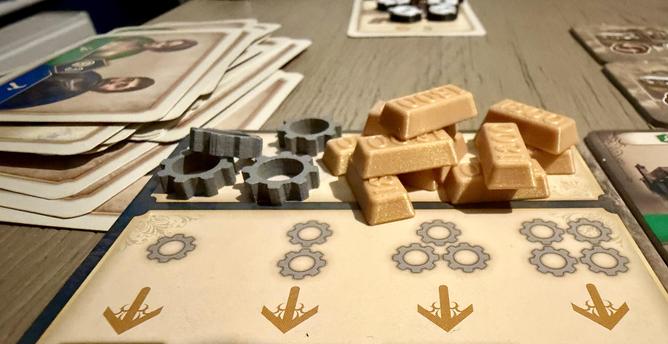Anno 1800 expansion board. Disarrayed pile of cards to the left. Gold bars in the centre.