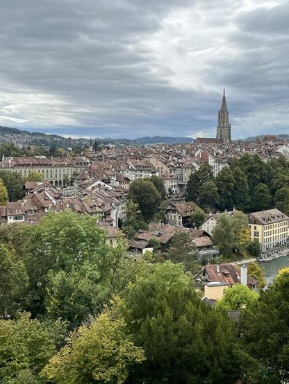 Blick von einer Anhöhe die Altstadt von Bern mit Aare und Münster, eine Regenfront zieht heran.