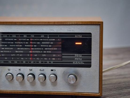 Detailansicht des Radios:
Man sieht die Skalenscheibe und rechts davon die Bereitschaftsanzeige -> Darüber ist kHz zu lesen, darunter MHz, MHz und Kanal.
Knöpfe für U K M Tonband und Stereo, sowie Sendereinstellung sind zu sehen.