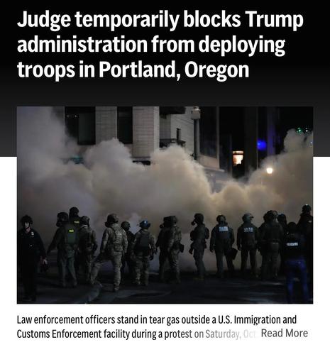 Image depicts law enforcement officers in tactical gear standing in tear gas outside a U.S. Immigration and Customs Enforcement facility during a protest in Portland, Oregon. Smoke fills the scene indicating a tense atmosphere.
