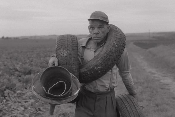 Denis Lavant carries tyres and scrap over a field in Redoubt