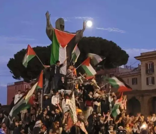 protestants waving many Palestinian flags near Saint Francis statue  at San Giovanni square, Rome