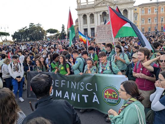 Un gruppo di scout sosta all'arrivo in piazza San Giovanni tenendo uno striscione su cui si legge la scritta "definisci umanità" e si vede il logo dell'associazione scout CNGEI.