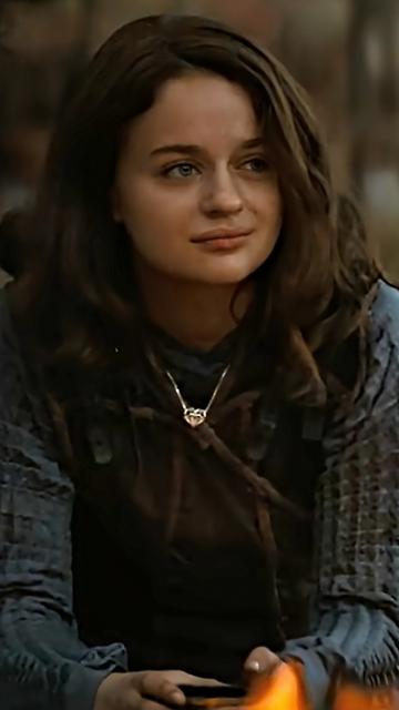 A shot from Netflix's Uglies of Tally Youngblood, played by Joey King, sitting contemplatively beside a campfire. She wears dark, rough textured clothing, and a silver heart shaped pendant necklace designed by Xover0. (See previous post for further description of the necklace.)