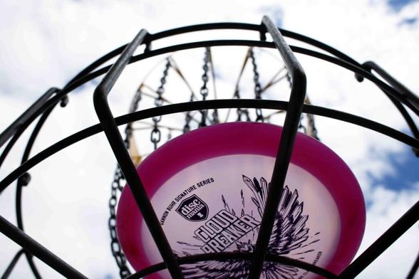 Photo taken from underneath of a frisbee sitting inside a basket outside.