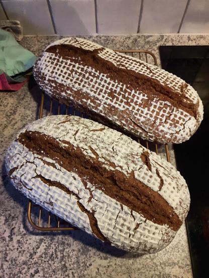 Zwei Laibe Brot auf einem Abkühlgitter.