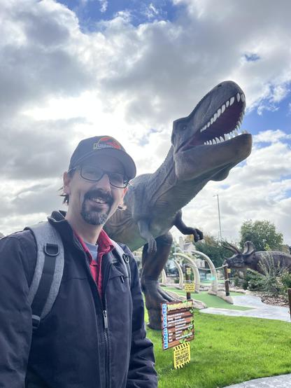 Me in front of a live size T. rex model on an adventure golf course.