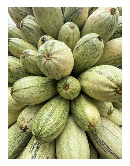 Fotografía de una pila de calabacines con gotas de agua