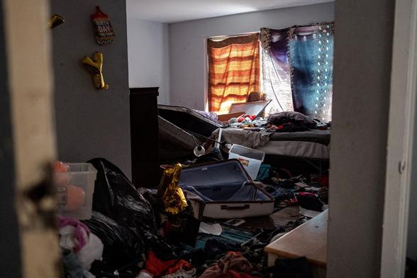 Вид разгромленной комнаты из коридора. Окно занавешено тремя разными шторами, пол завален тряпками, пустыми чемоданами, коробками и чёрными мешками, на стене висят некоторые золотистые буквы-шарики из надписи «Happy BDay», а также подарочные пакетики с пожеланием «Happy Happy Birth Day to You!» Так выглядит квартира в Чикаго после антимигрантского рейда силовиков из ICE. // A view of a ransacked room from the hallway. The window is covered with three different curtains, the floor is littered with clothes, empty suitcases, boxes, and black bags. A few gold letter balloons that spell out “Happy BDay” hang on the wall, along with gift bags with the wish “Happy Happy Birth Day to You!” This is what a Chicago apartment looks like after an anti-immigrant raid by ICE officers. // 2 or 3 October 2025 © Jim Vondruska, Reuters