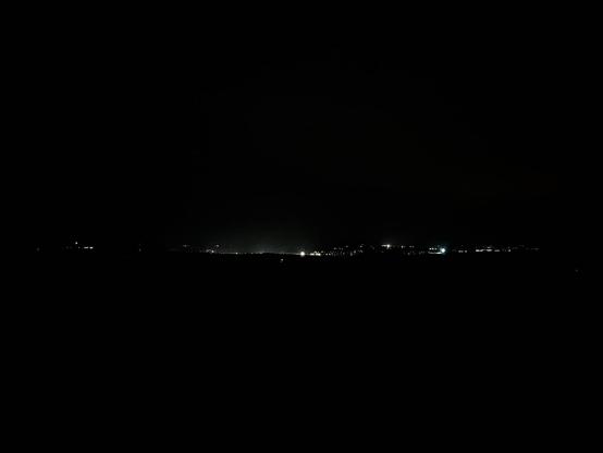 Night time now. Dark photo with just the lights from the next village in the distance.
