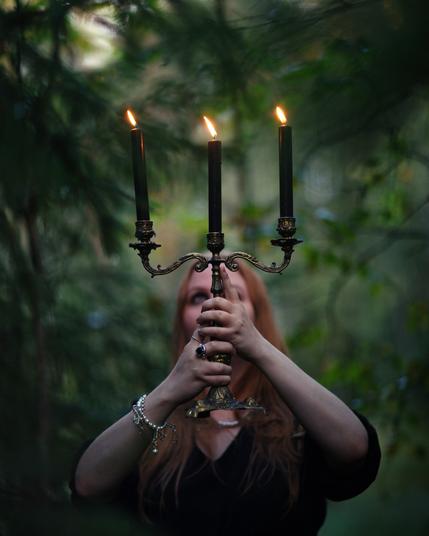 A witch holding a candle in an autumn forest