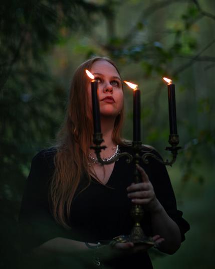 A witch holding a candle in an autumn forest