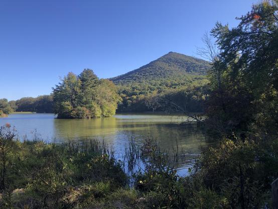 pyramid shaped green mountain across lake with an island full of trees