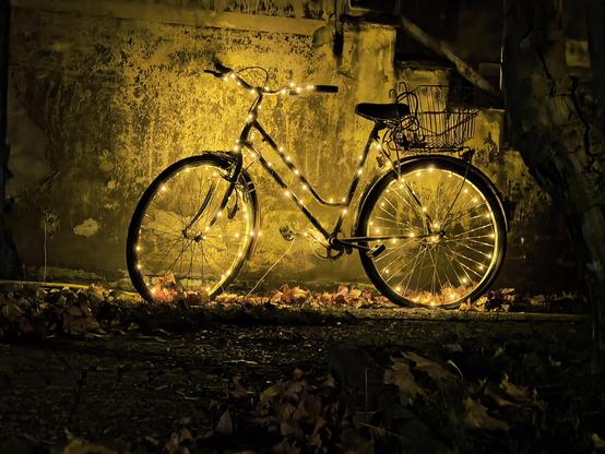 Nachtaufnahmen eines Fahrrads, das mit einer gelb leuchtenden Lichterkette versehen ist.