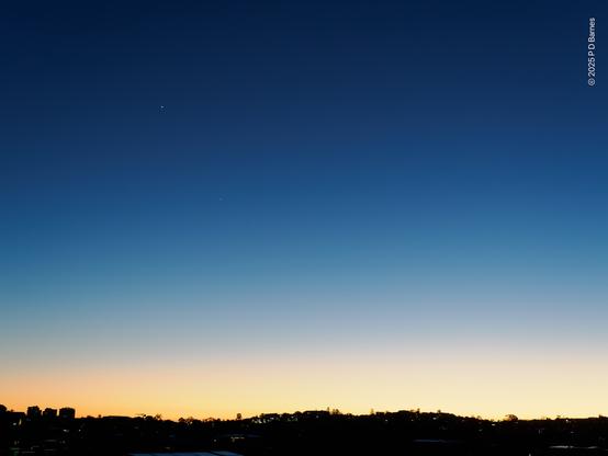 The frame is almost entirely blue sky, shading from deep blue at zenith to a lighter blue, then a pale yellow at the horizon