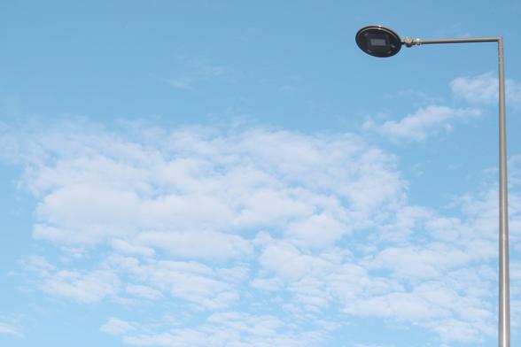 A blue sky with clouds grouped in a rectangle and a streetlight closing the frame at the right