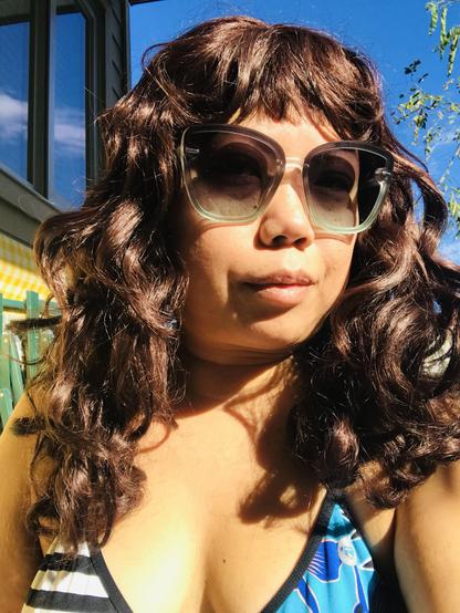 Crissy wearing sunnies and sunbathing outside in a bikini top
