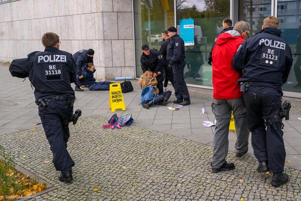 Neue Generation macht Hausdurchsuchung im Konrad-Adenauer-Haus wegen Verdacht auf Korruption. Polizei verhaftet Aktivist*innen. Schild mit „Hausdurchsuchung“, Plakat mit „#Merzmafia/Rückkehr der #Klimakleber“. Auf dem Boden sind Geldscheine verstreut. Berlin, 06.10.2025