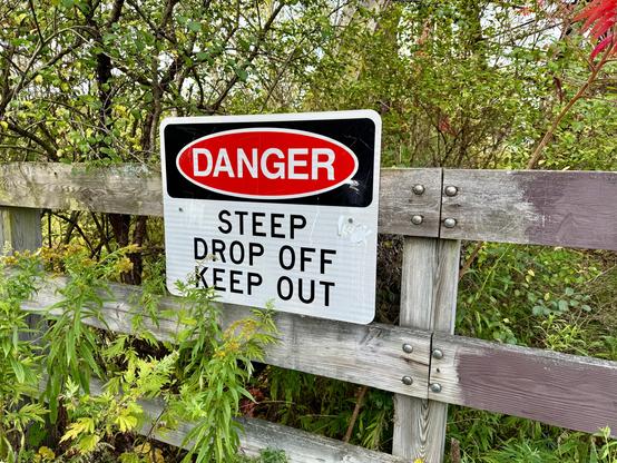 A warning sign indicating there's a steep drop off into a creek