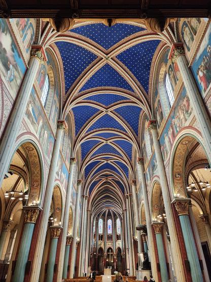 view directly down the nave toward the altar. dominating the scene is the deep blue vaulted ceiling with patterned stars. the columns are simple and the walls frescoed with biblical and hagiographical scenes.1