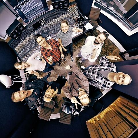 A 360° group picture of the band and the audio engineers inside the mixing booth