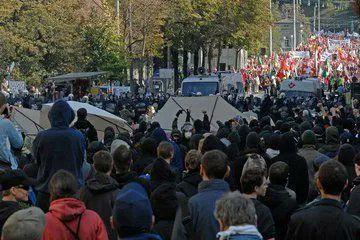 Große Menschenmenge vor einer Polizeikette. In der Ferne Aufmarsch der Faschisten.