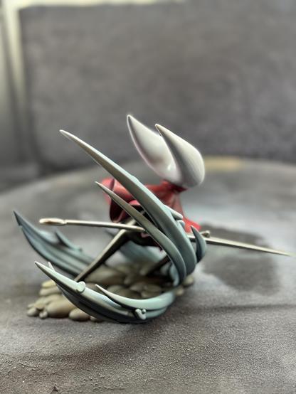 A 3d printed figure of Hornet from the game Hollow Knight Silksong. After airbrushing more shading and colors. The model is shown from the behind with more of the shading of the base.