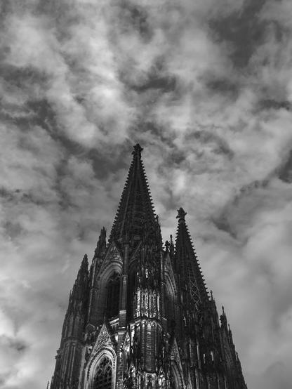 The towers of Cologne Cathedral against a dramatic backdrop of clouds. The perspective is chosen so that the towers appear to be touching each other.
