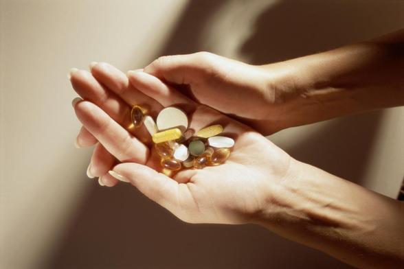 Manos de mujer con distintos suplementos vitamínicos. (Getty Images)