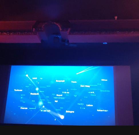 El mapa de Cines Europa de color azul profundo, salpicada de numerosos puntos blancos y luminosos que representan ciudades. Delgados haces de luz y líneas blancas conectan varios de estos puntos, formando una especie de constelación o red de viajes.

Entre los nombres de ciudades europeas visibles se encuentran Lisboa, Copenhague, Bolonia, Maastricht, Florencia, Reikiavik, Toulouse, Nápoles, Bucarest, Trieste, Vilna y La Haya. Algunos de los puntos de la red emiten haces de luz más intensos, sugiriendo actividad o conexiones principales.