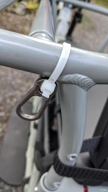 Small metal clip in a carabineer shape zip tied to monkey bars