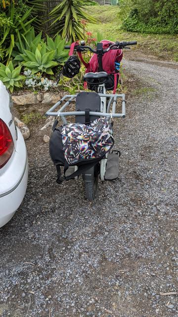 Full bike from rear, bag is slung between the rear corners, blocking the rear light.

A school bag is in the front basket.