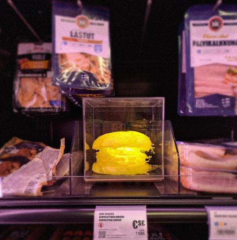 Anne Roininen's Geopolitical Burger, part 1: A yellow glowing burger in a prepared food section of Alepa