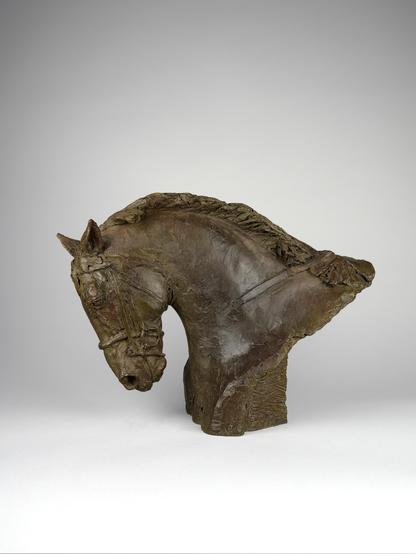 Photographie d'une sculpture en bronze représentant une tête de cheval de sport harnachée