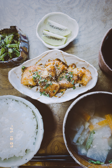 It’s fried atsuage with ginger sauce. It’s sprinkled with sesame and chopped green onion. It’s served on an uneven dish I made. The dish have irregular lines. Around the dish, there are some other dishes which have some foods.