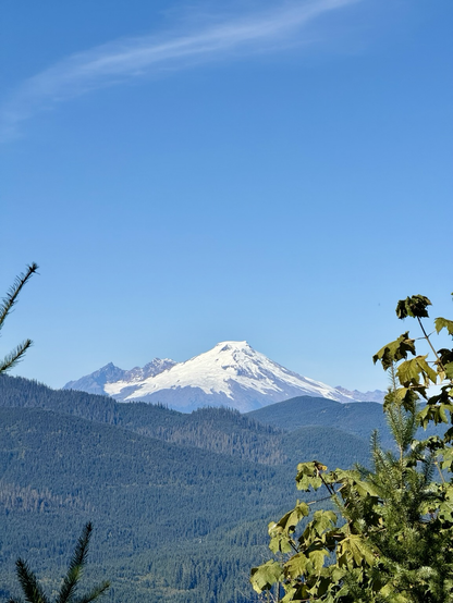 A snow capped stratovolcano in the distance under an azure sky