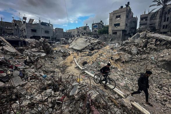 Unos palestinos caminan entre ruinas en el campamento de refugiados de Khan Yunis, en Gaza, el 27 de noviembre de 2023. (Mohammed Salem / REUTERS)