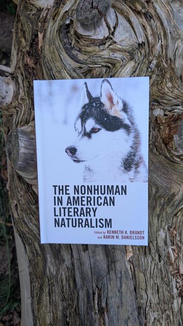 The book "The Nonhuman in American Literary Naturalism" on a large tree trunk