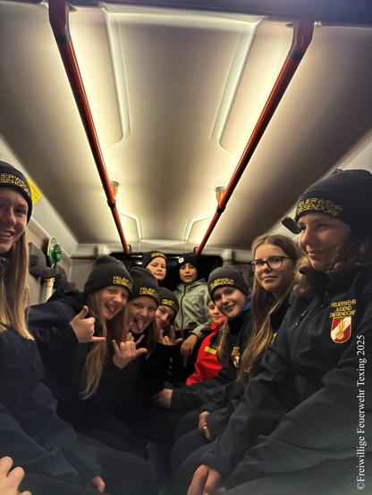 Mehrere Mitglieder (Burschen und Mädchen) sitzen im Mannschaftsraum eines Einsatzfahrzeuges der freiwilligen Feuerwehr Diesendorf. 

Die Kinder lachen und schneiden Grimassen. Alle tragen eine Haube mit der Aufschrift "Feuerwehrjugend Diesendorf". 

English: 
Several members—both boys and girls—are seated in the crew compartment of a volunteer‑firefighter vehicle from Diesendorf.

The children are laughing and pulling funny faces. Everyone is wearing a cap that reads “Fire‑brigade Youth Diesendorf.”