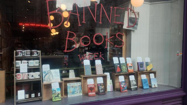 A close up of the bookshop window for Banned Books Week, books arrayed in the display, sporting an explanation of some of the ways people have tried to have them banned.