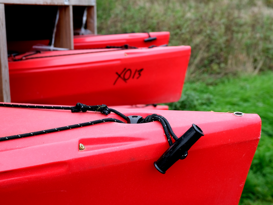 The noses of three red kayaks