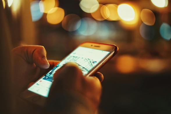 Yellowish pixelated image at night. Person holding a phone looking at an image of a building