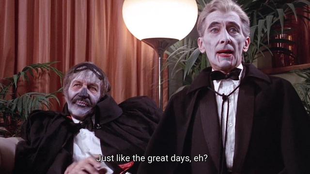 For a costume party, Peter Cushing is dressed as a vampire with white face paint and blood dripping down his face. Vincent Price is beside him with skeletal face paint. Peter says, "Just like the great days, eh?"