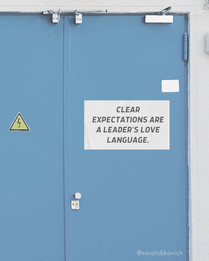 A blue door with a sign that reads, "Clear expectations are a leader's love language." A small electrical warning sign is also visible on the door.